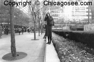 Woman photographer standing alone shooting a parade